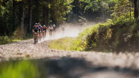 Red On Sports A group of cyclists create a dust cloud along a route through Galloway forest