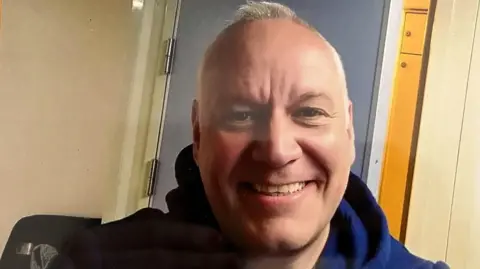 Family handout Glenn Perkins smiling for the camera in a selfie, taken in a small room.