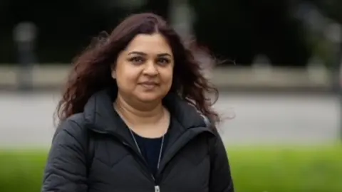 Tanya Nasir wearing a black coat