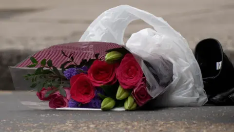 PA Media A bunch of cerise roses laid on the ground