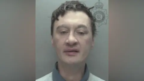 Humberside Police A man with messy short black hair in a police mugshot. His eyes are half-closed.