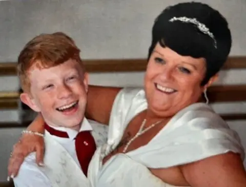 Kevin Page A young man with red hair and a white shirt and a woman with short black hair and a white dress pictured at a wedding