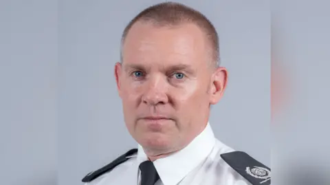 Norfolk Fire and Rescue Service Emyr Gough, from Norfolk Fire and Rescue Service, in a white shirt and black tie with epaulettes on his shoulders.