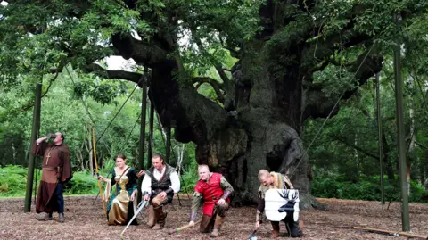 PA Media Modern actors portraying characters from Robin Hood stood by the Major Oak