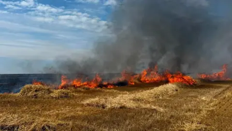 Cornwall Fire and Rescue Service large orange flames and thick black smoke erupting from a dried out patch of grassland in Cornwall.