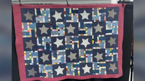 Edd Smith/BBC Quilt with a red border and blue squares with white and grey stars