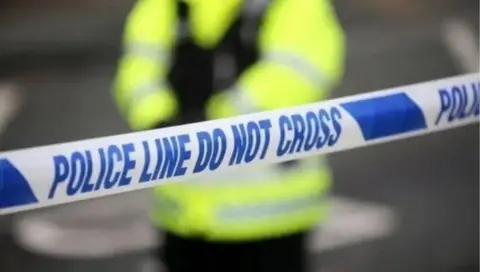 A stock image showing a police cordon and a police officer stood inside the cordon. 