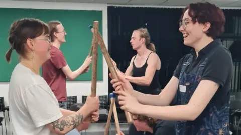 Ramshackle Morris Morris dancers face each other, hitting wooden sticks. 