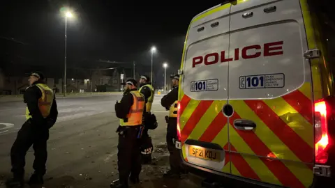 four police officers standing beside a police van