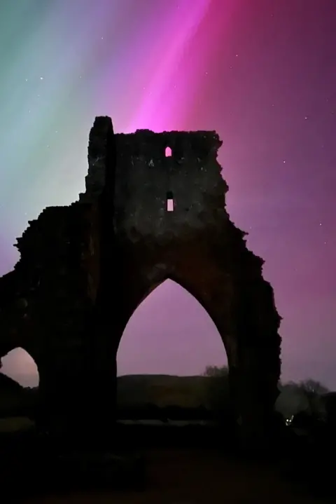 Mel Gribble Castel ruins silhouetted against pinkish hues