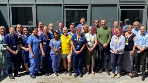 DCH Members of DCH’s urgent and emergency care and medical teams gather in a courtyard outside the current Emergency Department.