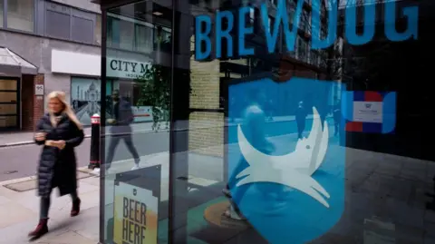 Getty Images A woman walks past a Brewdog pub, which has the firm's name and logo in the window.