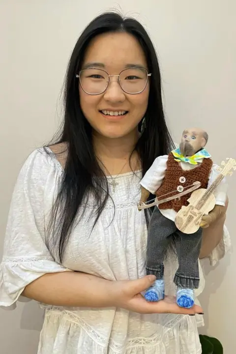 LILY-JOY LANCASHIRE Lancashire holding the puppet, which is holding a small fiddle.