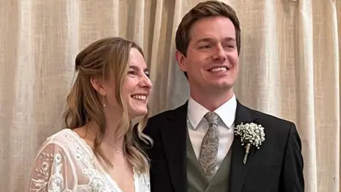 Rebecca and George Lance, smiling in their wedding outfits