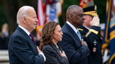 US President Joe Biden (L), Vice President Kamala Harris (2-L) and Secretary of Defense Lloyd Austin (3-L) look on during the pledge of allegiance 