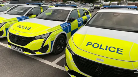 Line of police cars, with fluorescent yellow fronts and the word POLICE in capitals letters on the bonnets.