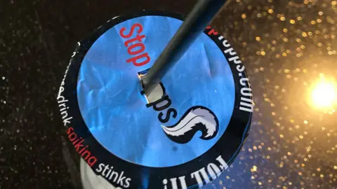 A drink with a cover on top of it to prevent spiking