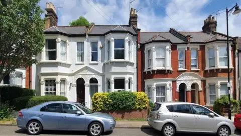 Getty Images A row of houses in Islington in London - they are town houses with a Victorian-era design. Cars are visible in the street in front of the properties and it is a clear day 