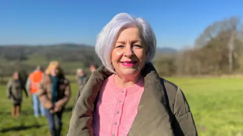 Woman with white hair and pink lipstick in a sunny field