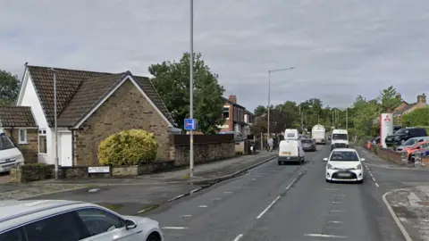 Edwin Williams Grimsargh today showing a busy asphalt road, a car garage to the right and a large bungalow to the left