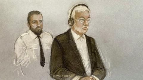 A court sketch of Hongchi Xiao today at Winchester Crown Court. He is shown wearing a dark suit jacket and white shirt with no tie, black headphones and glasses. Behind him is a custody officer in a white shirt and dark tie. 