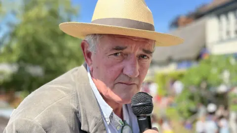 Tim Finney speaking into a microphone as he commentates on the four races