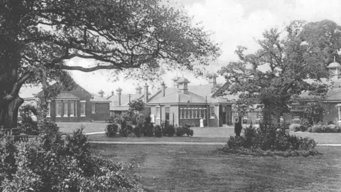 Findmypast Una foto en blanco y negro del Asilo Manor con jardines en primer plano