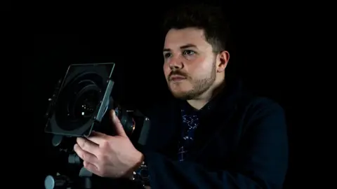 Josh Dury Photo-Media A man pointing a large camera lens up to the sky