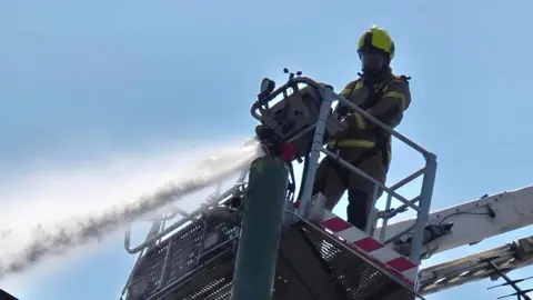 Leicestershire Fire and Rescue Service Water being hosed from an aerial platform by a firefighter in kit