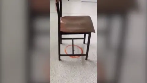 A chair placed over a red circle, drawn around a bullet shell on the floor