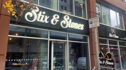 BBC An image of Stix and Stones, a glass display case with a black panel with white font "Stix and stones."