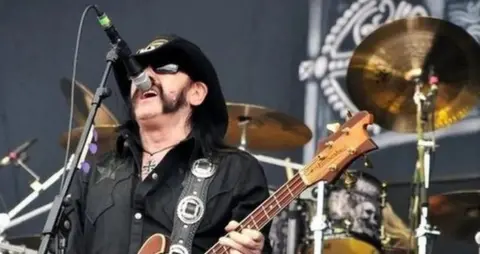 Motorhead frontman Lemmy holding a guitar and singing into a microphone