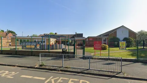 Single storey school buildings and a colourful playground behind a fence. A sign reads "St Paul's C of E Infant School".