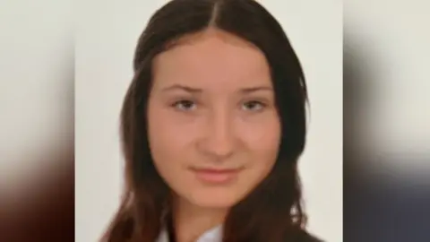 Family handout A teenage girl with long brown hair looks at the camera. She is wearing a white shirt, a navy and white striped tie and a navy blazer.