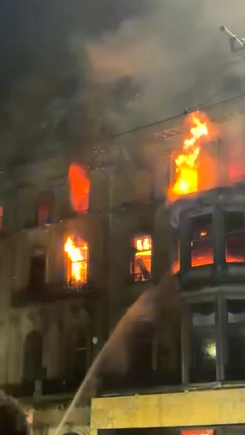 Large flames erupting from upper windows of a building on Princes Street