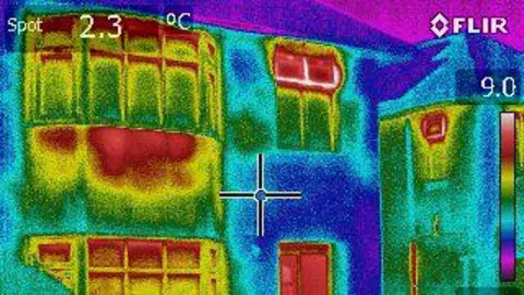 A thermal imaging camera image of a house. The colour scale is from dark purple to bright yellow. The home is two storeys and detached.