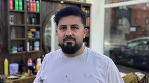 BBC A man standing in a barber shop with a beard 