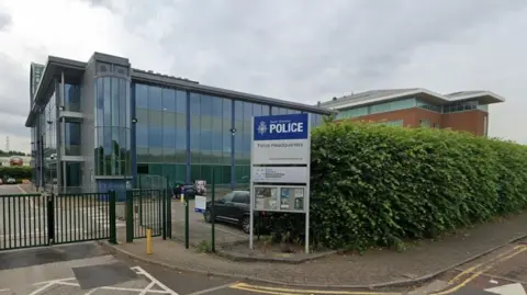 A general view of the headquarters in Carbrook Hall Road. A sign with the police logo is positioned next to the entrance gate and in front of the glass front of the building.