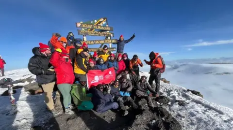 Foundation for Women and Children in Birmingham trust more than 20 people together at the top, along with snowy and ice scenes. Some people wear a red flag.