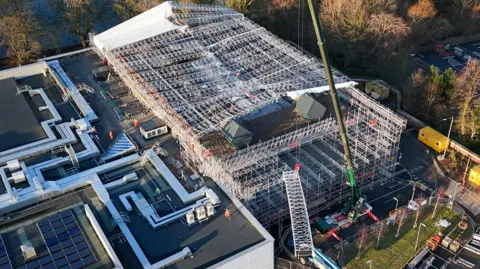 Cumberland Council An aerial view of the Sands Centre which is covered in scaffolding. There is a large crane in the foreground and part of a white, temporary canopy 