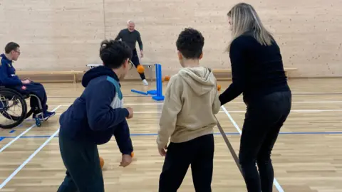 West Essex Inclusion Project The group play cricket together, taking it in turn to throw and bat the ball.