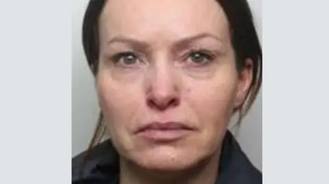 A picture of Lauren Millington's mugshot. She has brown hair tied back and appears to be crying or has been crying.