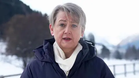Yvette Cooper speaking to BBC Breakfast from Davos, in Switzerland dressed in a blue winter coat and white scarf, against a snowy backdrop