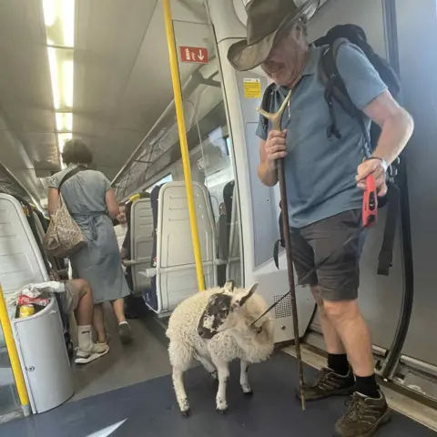 Michelle Robertson Another photo from Michelle of Jai and NJ stood near the doors of the train. H had the sheep on a long retractable dog lead.