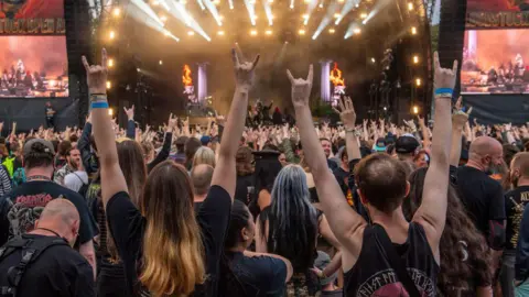 Getty Images A sea of people facing the crowd with their hands up.