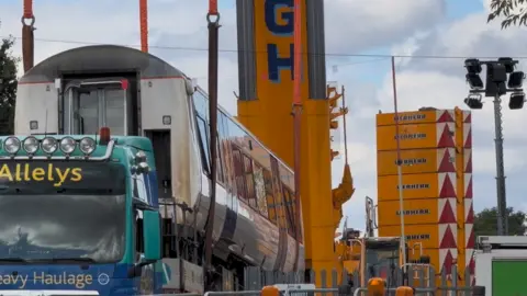GILES HAYE A close-up of the carriage being lifted by a crane onto a yellow haulage vehicle