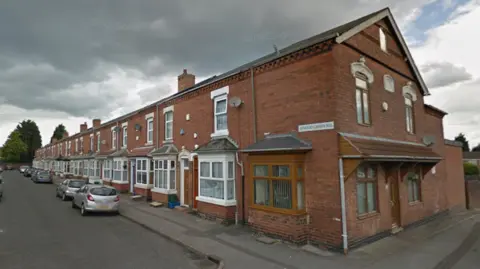 Generic street view shot of a red-brick Victorian terrace with bay windows fronting on to the pavement and cars parked along the street