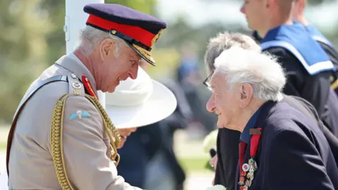 PA Media D-Day veteran Albert Keir wearing military medals shakes hands with King Charles in Normandy at D-Day commemorations, King Charles in military dress