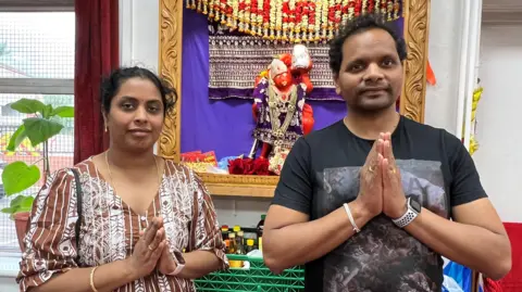 Satish Kumar Divvela (L) and Annapurna Divvela (R) they are behind a Hanuman statue. 