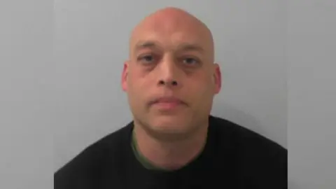 National Crime Agency A mugshot of Nathaniel Benson, who has a shaved head and is wearing a black jumper